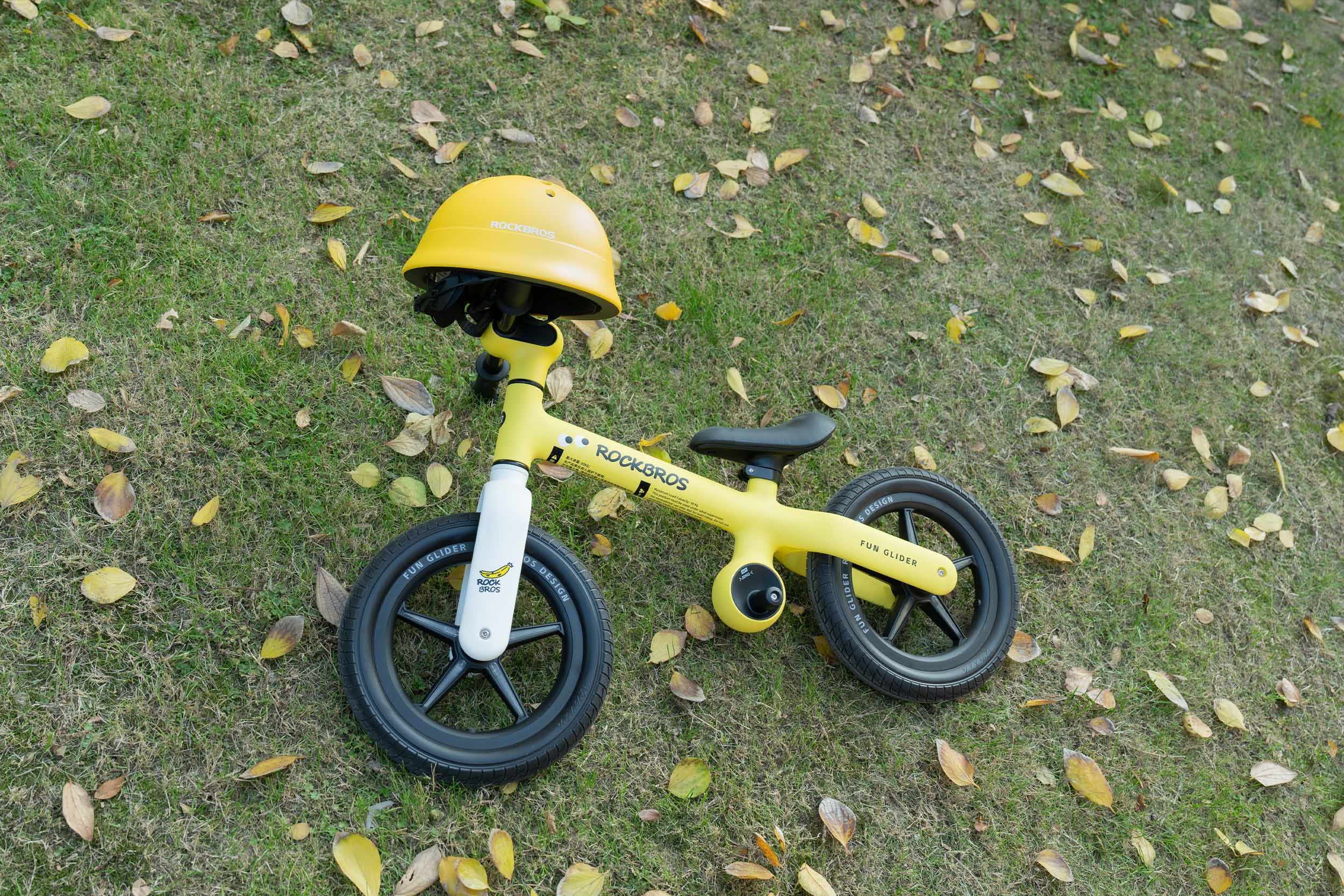 A vibrant yellow ROCKBROS balance bike for toddlers compared with a traditional bicycle, featuring a safety helmet - ideal for learning balance skills.