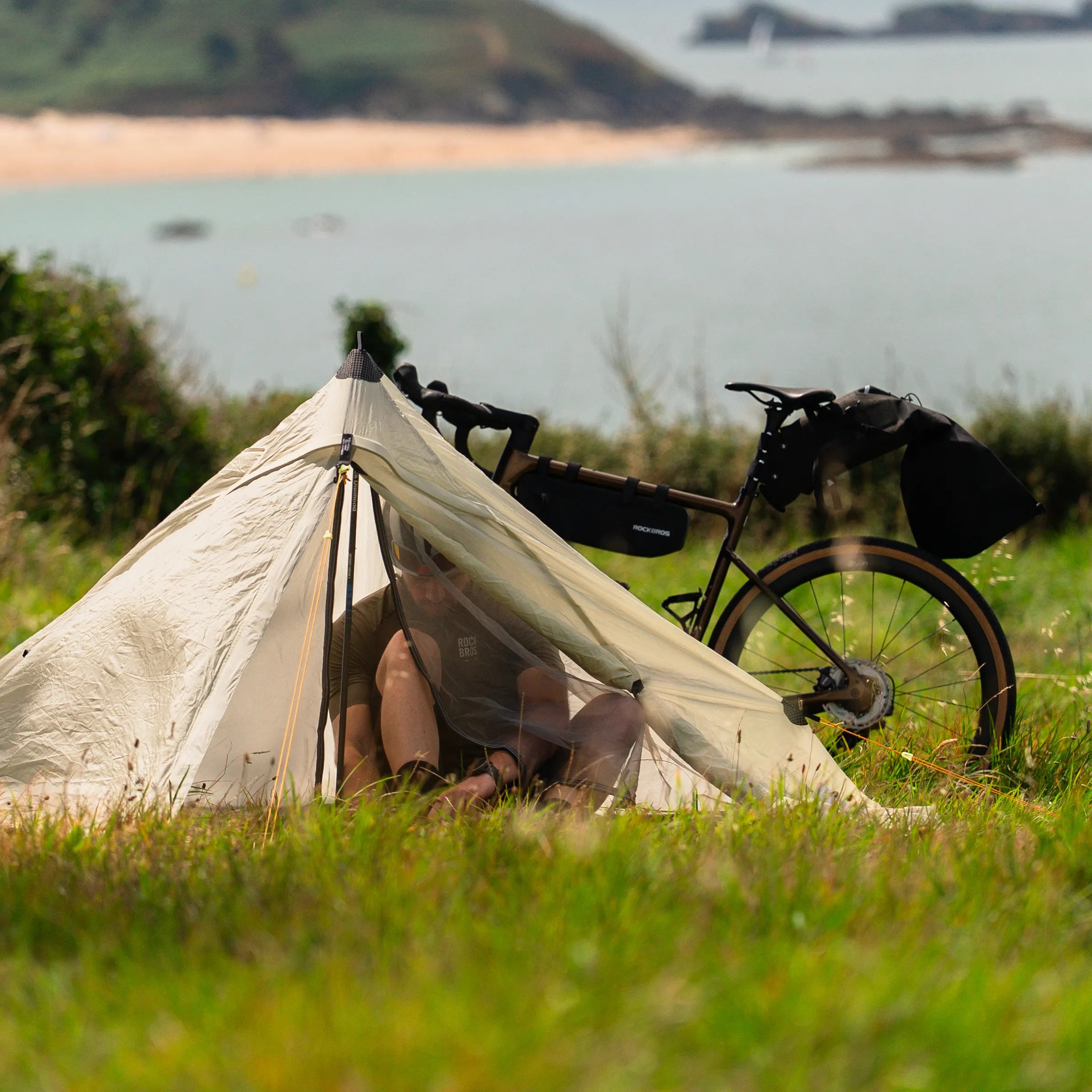Bikepacking cyclist riding a gravel bike with frame bags and camping gear on a mountain trail