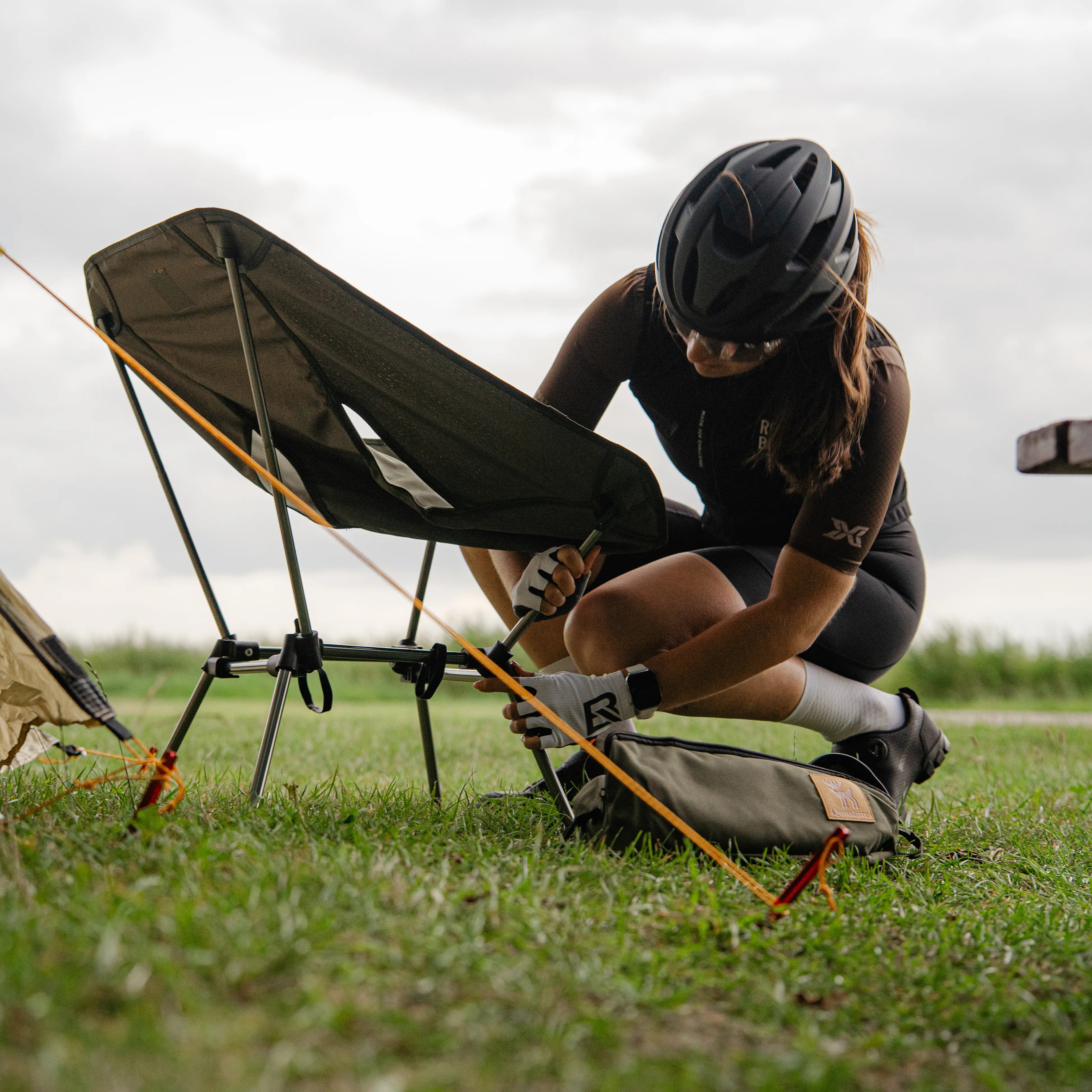 Cyclist camping beside a gravel bike equipped with bikepacking bags and outdoor gear