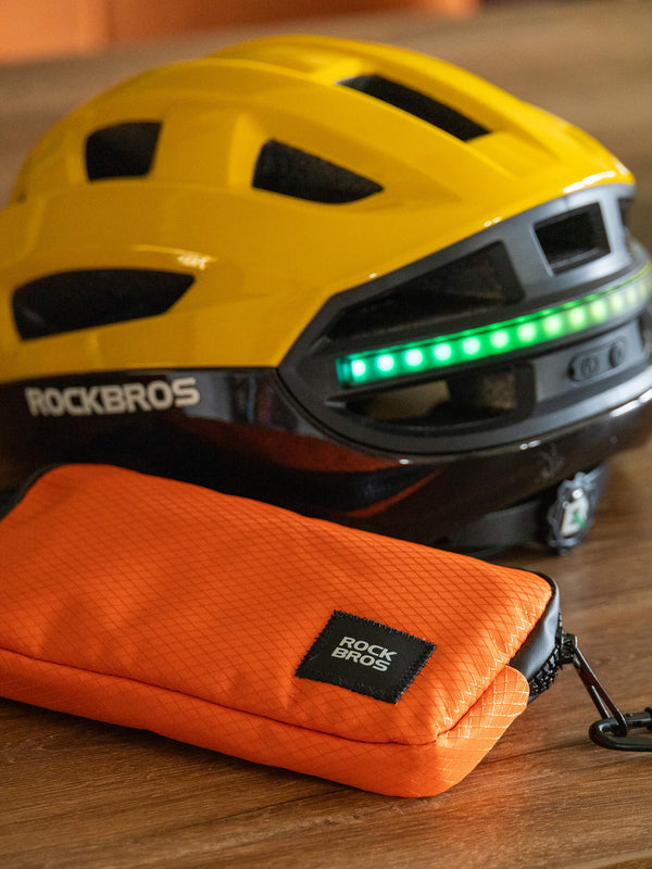 Yellow helmet with green lights and orange carrying case on a wooden surface